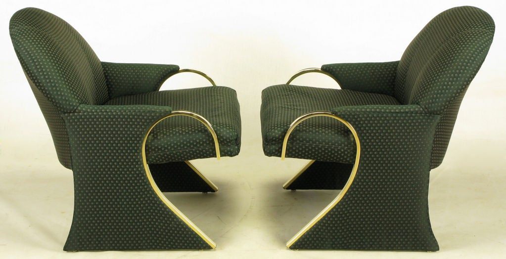 Sculptural sled base art deco revival lounge chairs with curved brass detailed arms that continue down the front of the sled base. The arms evoke some designs by Pierre Cardin.  Upholstered in a dark green pin point silk blend upholstery.