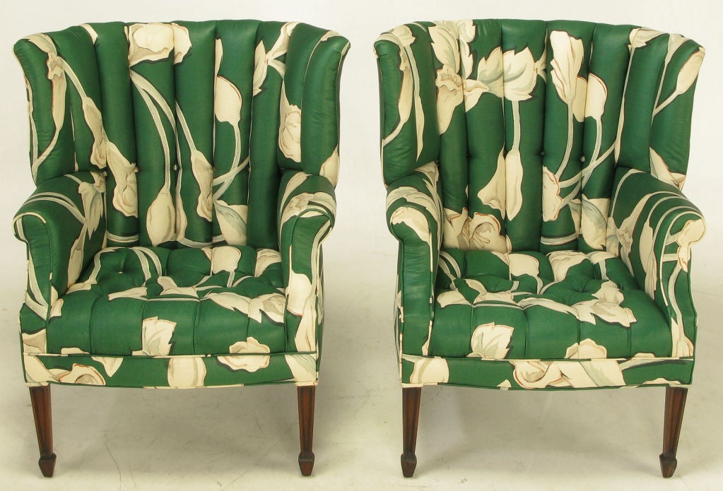 Pair of uncommon curved & channel back wing chairs in a newer large floral print polished cotton upholstery. Button tufted and channeled seats with rolled arms. Mahogany frames with recessed panel front legs with reverse obelisk feet.