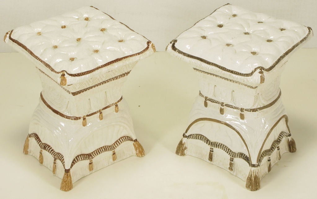Pair of white glazed Italian majolica garden stools. Button tufted looking seats with brown glazed buttons, stitching and tassels. Exact same seat with minor differences in the brown and gold color hand painted details.