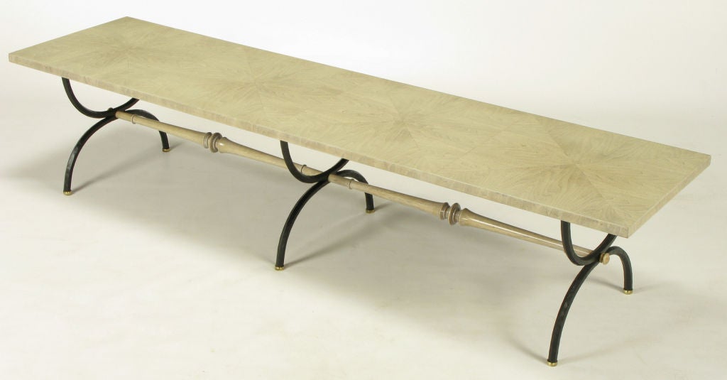 Beautifully refinished Tomlinson iron curule leg coffee table in a bleached walnut with driftwood grey glaze. The triple curule form hammered iron legs are lacquered satin black and spaced by carved wood stretchers with the same glazing as the top.
