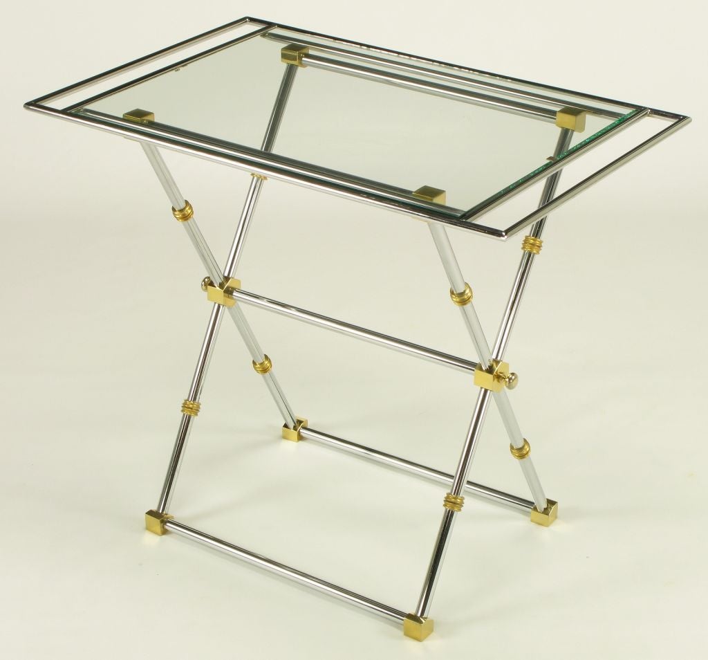 Verchromter Stahl mit geometrischen Messingverbindern und gerippten Messingringdetails am zweiteiligen X-Rahmen-Tisch. Das abnehmbare obere Tablett ist ein verchromtes Tablett in einem anderen verchromten Rahmen, der an den Enden verlängert ist und