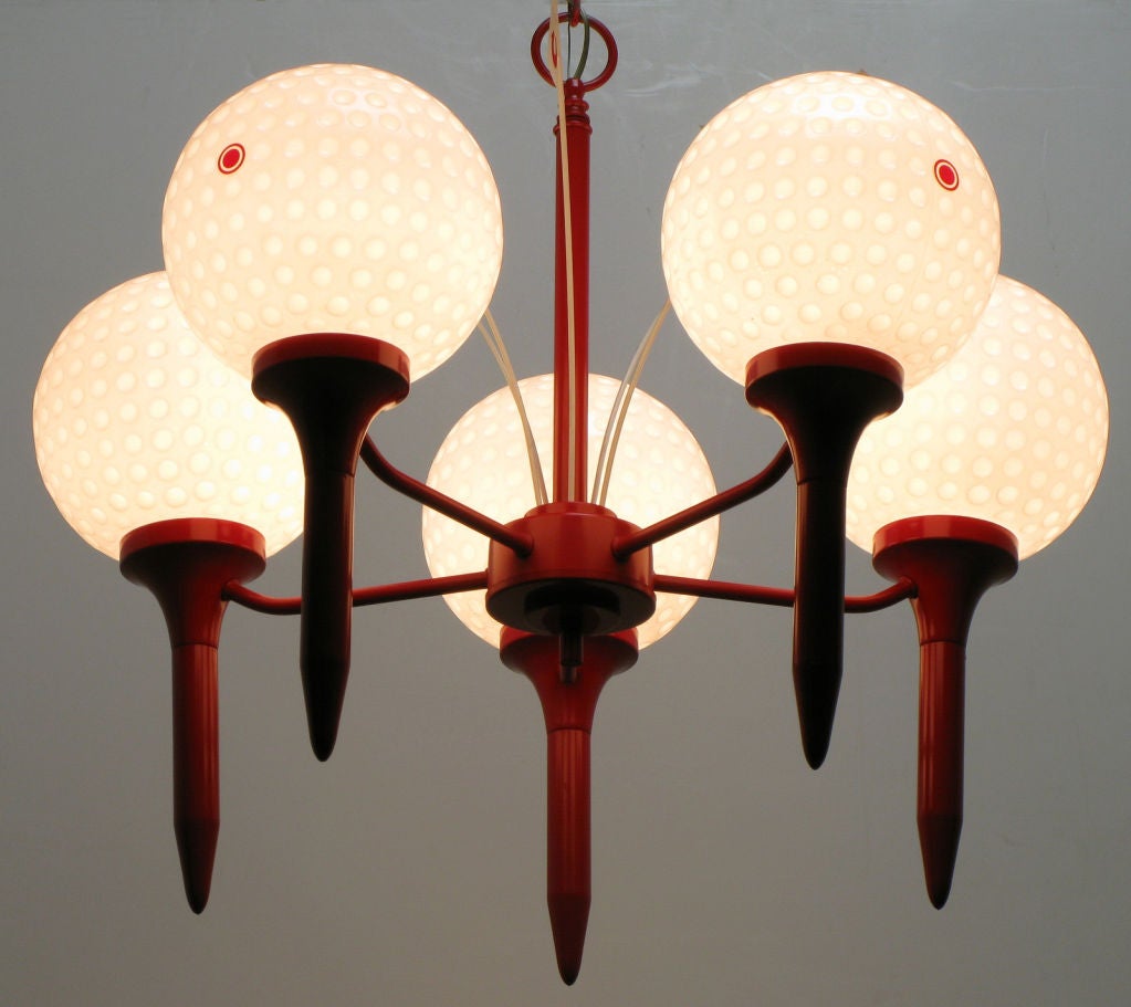 Unusual and striking golfer's dream chandelier. Red lacquered metal frame in the shape of golf ball tees connected by arms to the center post. Globes are dimpled heavy glass golf balls.  In the center disc are five flags numbered 1, 3, 5, 7 & 9.