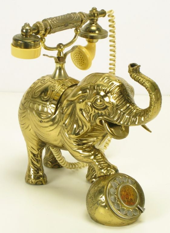 Unusual elephant form cast brass telephone with cast brass ball rotary dial and brass toned handled and ivory resin receiver. Center of rotary dial has a painted Asian village scene.  For decorative use only, although it could be restored to work