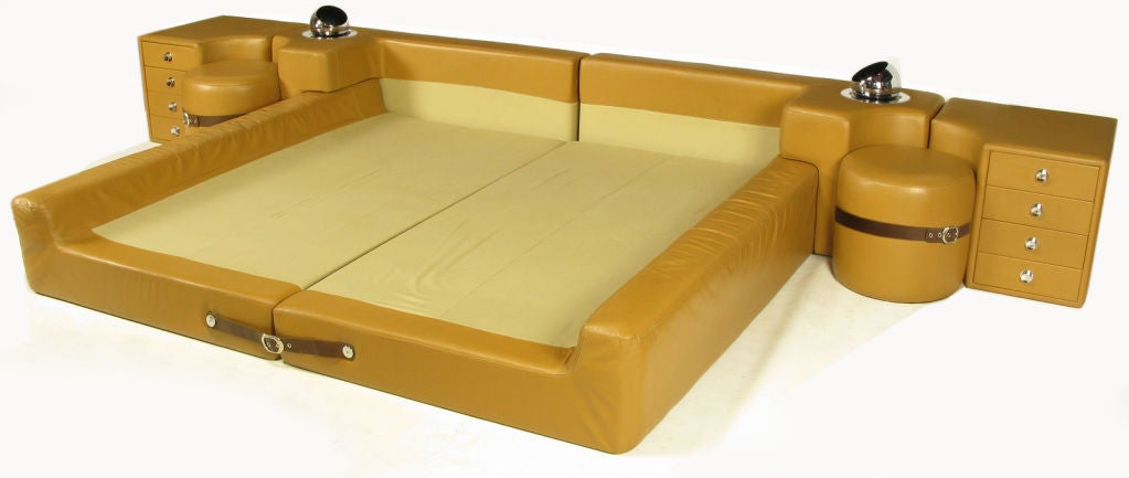 Pace Mariani leather clad king size low platform bed with leather straps and chromed buckles. Ensemble comes with two leather over wood night stands. Chrome pulls and form fitted leather ottomans fix to the nightstands and bedside with leather