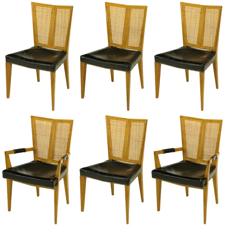 Set of six rare V-back dining chairs. Clean lines, excellent construction and unique form.  Includes two arm chairs and four side chars. Each chair has a bleached walnut frame, with V-shaped two-piece cane back, leather seat with brass nail head