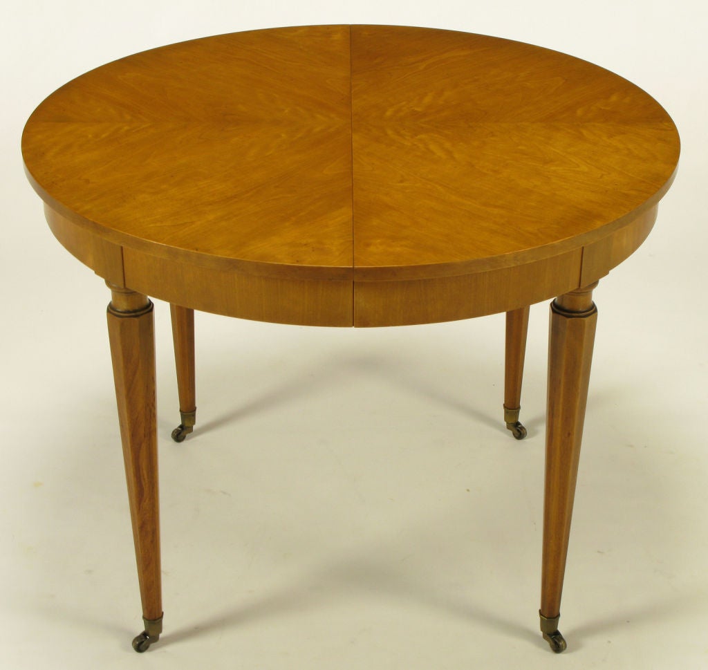 Well made and beautifully grained parquetry top round regency dining table. Tapered hexagonal legs finish with brass sabots and casters. Possibly by Union National of Jamestown, NY, with quality similar to vintage Baker or Henredon.  Extends to 70