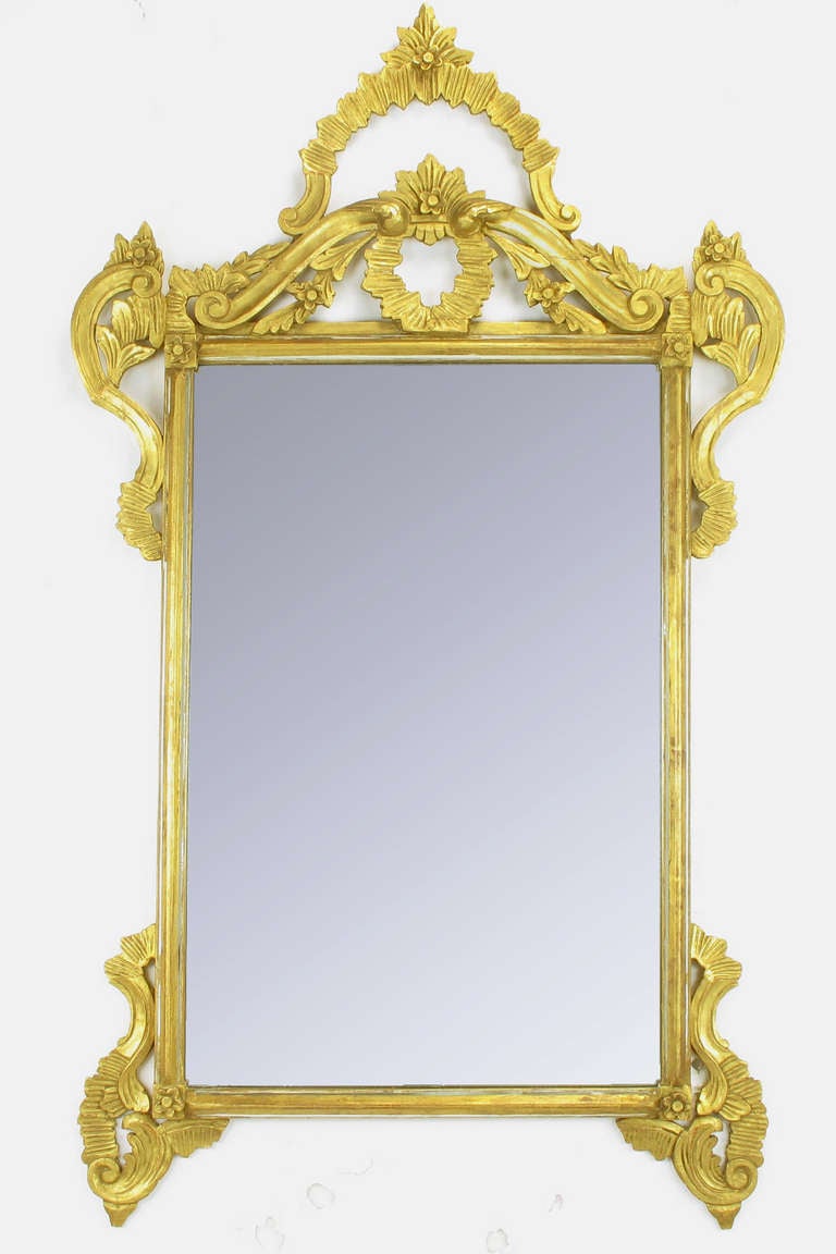 Early 1900s Italian hand carved and gilt wood framed mirror. Open pediment with linen folds and floral rosettes; bracketed at every corner. Some older repairs, well executed but visible, see image 4. 