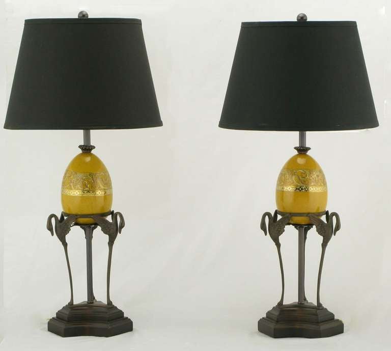 Excellent pair of bronze Empire revival table lamps by Fredrick Cooper of Chicago. Stepped plinth is carved wood trefoil. Three swans support a ceramic ostrich egg with a saffron crackle glaze and hand-painted gold leaf ornamentation. Sold sans