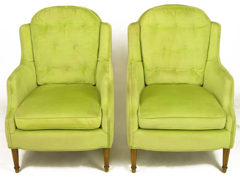 Elegant and comfortable chartreuse silk velvet Regency lounge chairs. Tall arch top backs with fixed button tufted cushions, slight wings and loose cushion seat. Fluted walnut front legs with tapered walnut back legs.