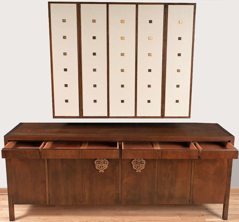 By Bert England for Johnson Furniture, this long walnut sideboard cabinet has flush drawers over doors adorned with large brass filigree drop pulls. Additional drawers and storage space behind the doors in this base cabinet.

As originally