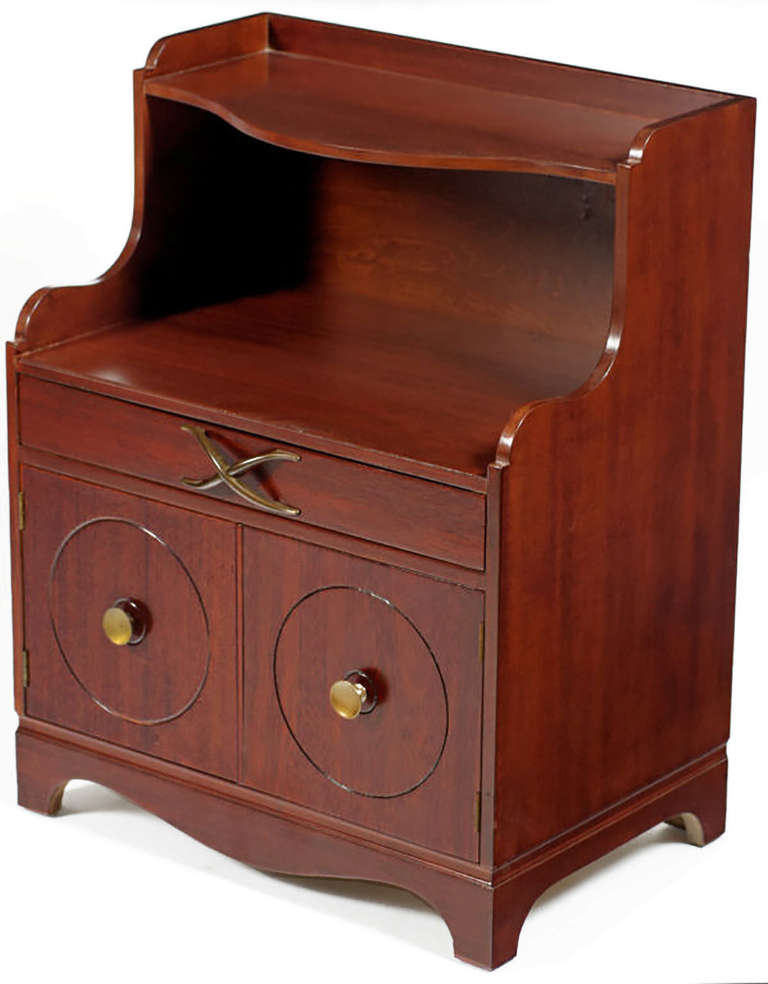 Great pair of mahogany nightstands, attributed to Lorin Jackson. Each has one drawer with a brass X-pull, and storage below behind doors, with both doors having round brass knobs echoed with round carving in the door. These will be refinished prior