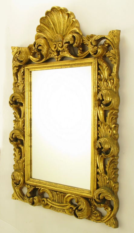 French Regence style mirror with deep relief filigree and shell surmount. Finely cast resin with gilt finish pressed on wood backing.