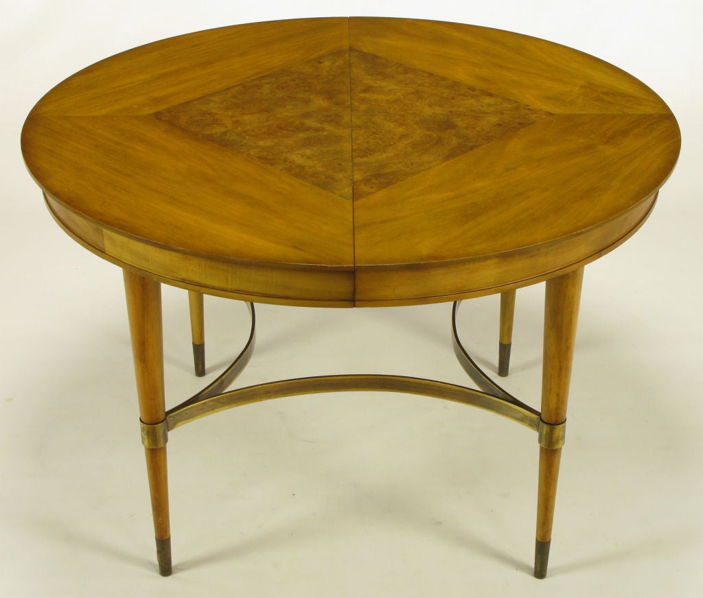 Round bleached walnut dining table by the revered J.L. Metz Company of Hammond, Indiana. Burled olive ash diamond inlaid top with reverse quatrefoil brass bar stretcher and cuffs. Reminiscent of Paul McCobb designs with the aforementioned stretcher
