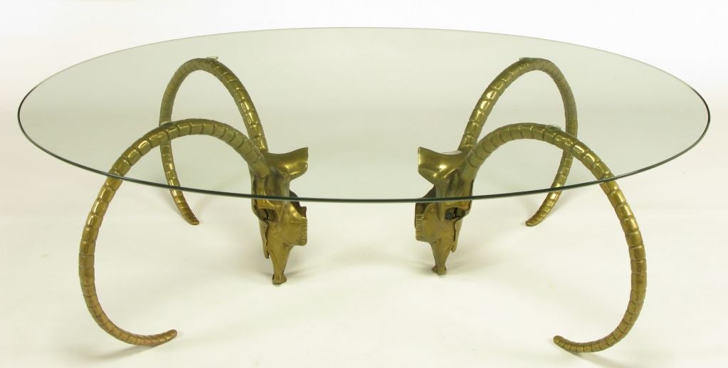 Brass horned ibyx skull coffee table base. Reverse direction of the horns making an unexpected brass two part coffee table base, allowing the skull of the animal to be seen from the side and the front. Oval 3/8