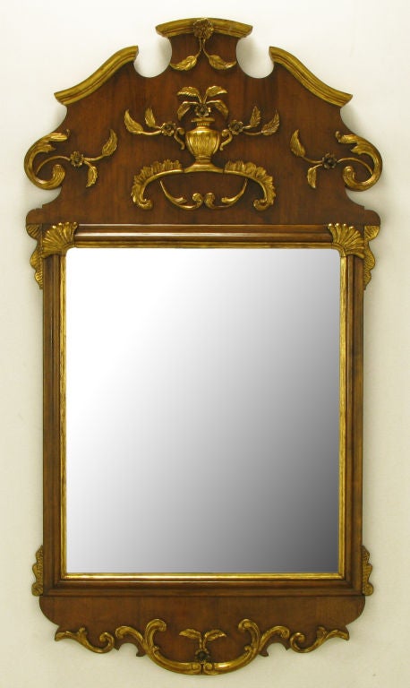 Walnut wood with carved and gilt Italianate detail style mirror. Top detailing features a floral accented urn and rococo style filigree. Carved and gilt bracketed corners and bottom filigree. Measures: 58