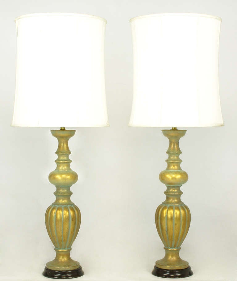 Pair of expertly crafted gilt plaster baluster style table lamps with applied patina. Excellent build quality as they weigh approximately 25lbs each, outfitted with a solid brass double socket cluster and ebonized resin plinth base. Sold sans