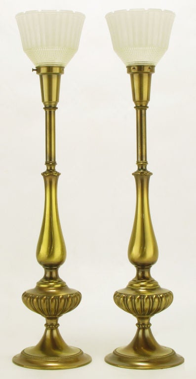 Elegant pair of solid brass regency style table lamps from Rembrandt Lamp Company. Flanged base with egg and dart body that resembles the oil basins of pre-electric lamps. Antique lacquer finish with original glass diffuser. Sold sans shades.