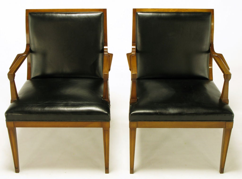 Pair of Stow Davis Italian regency carved walnut and black leather arm chairs. Sinuous back and saber legs with recessed panels, block corners and sculpted arms. Black leather seat and back with back panel.  From the period when Bert England was
