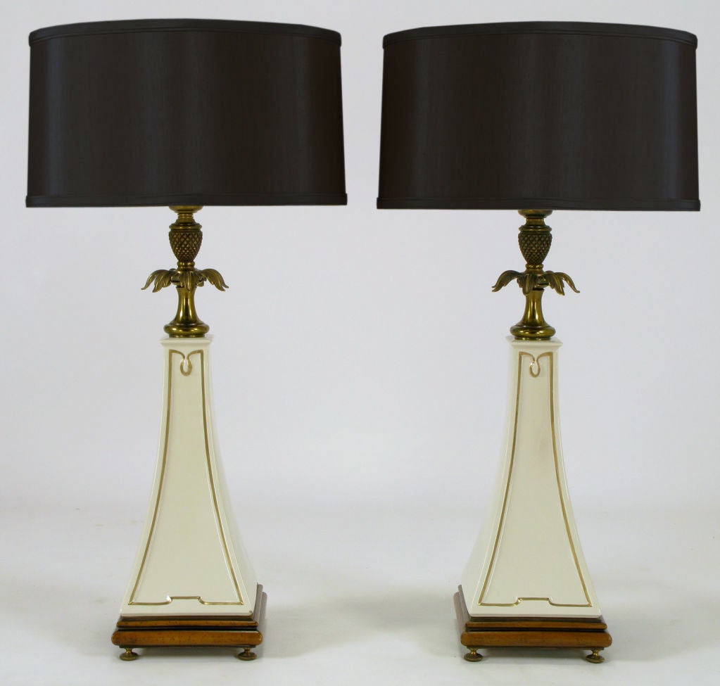 Pair of Stiffel neoclassical table lamps with Lenox porcelain obelisk bodies detailed in gilt edging. Wood base with brass feet, brass decorative pineapple and leafed spacer. Brass stem and cup with milk glass diffuser.