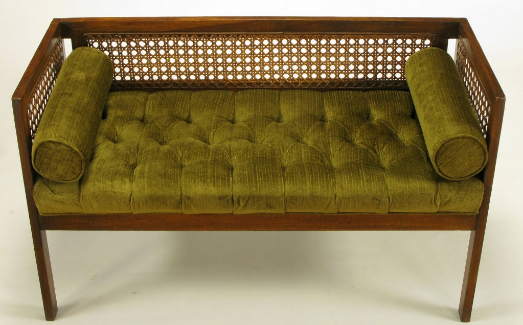 Even arm aged walnut finished bench with cane back and side panels. Walnut glaze over wood with speckled patina. Upholstered in a moss green velvet that is button tufted with two bolsters. Perfect end of the bed or entryway bench seat.
