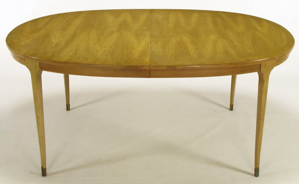 Bleached & figured walnut classic 1950s dining table in the manner of Harvey Probber. Clean tapered  legs with slight saber curve and brass sabots. Beautifully figured wood grained top with two 16
