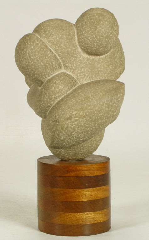 Carved stone sculpture mounted on a stacked wood cylinder base entitled 