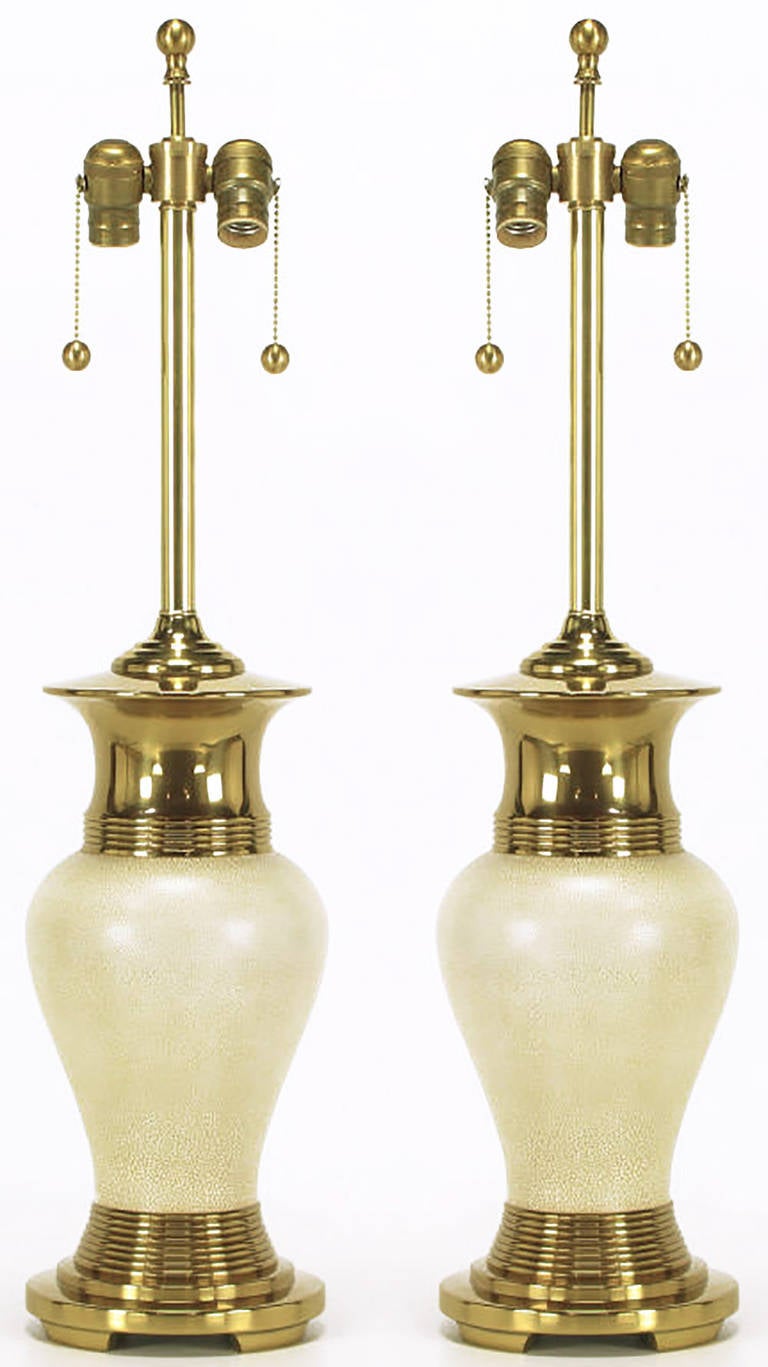 Pair of modern table lamps with heavy brass open footed basses and flanged vase form tops. The vase form body is ivory crackle glaze over brass. Brass stem and dual socket cluster with brass ball pull chains. Sold sans shades.