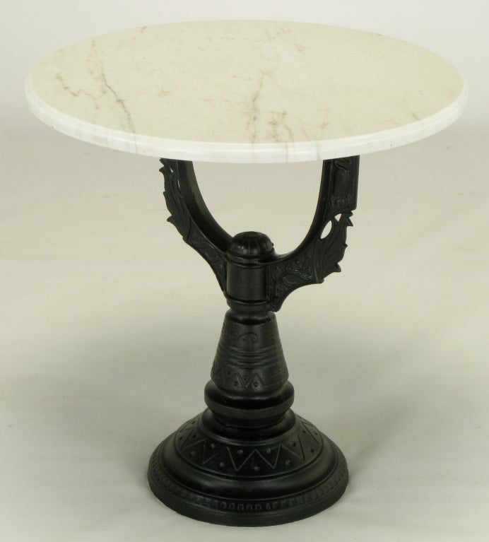 Cast and pierced iron based side table with marble top. Most probably created with the lower half of a prewar street lamp globe housing. Excellent casting with crisp lines and finished in a satin black lacquer. White Carrara marble-top sits atop a