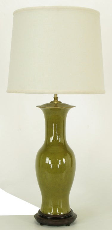 Warren Kessler ceramic vase-bodied table lamp. Excellent crackle glaze on olive green. Carved wood base with brass cap and stem, double socket cluster.