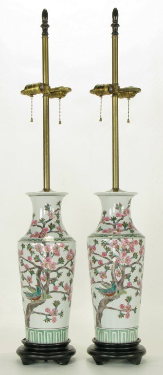 Chinese porcelain vase bodied table lamps with hand painted cherry trees in bloom and birds. Black lacquered carved wood base, brass cap, stem and double socket cluster. Sold sans shades.