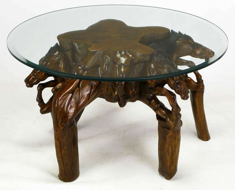 Expertly crafted work of art, this coffee table is hand carved from wood, stained and burnished, then polished. Galloping horses appear to be coming from the center of the table base. Legs are carved to resemble wood posts. Glass top is beveled and