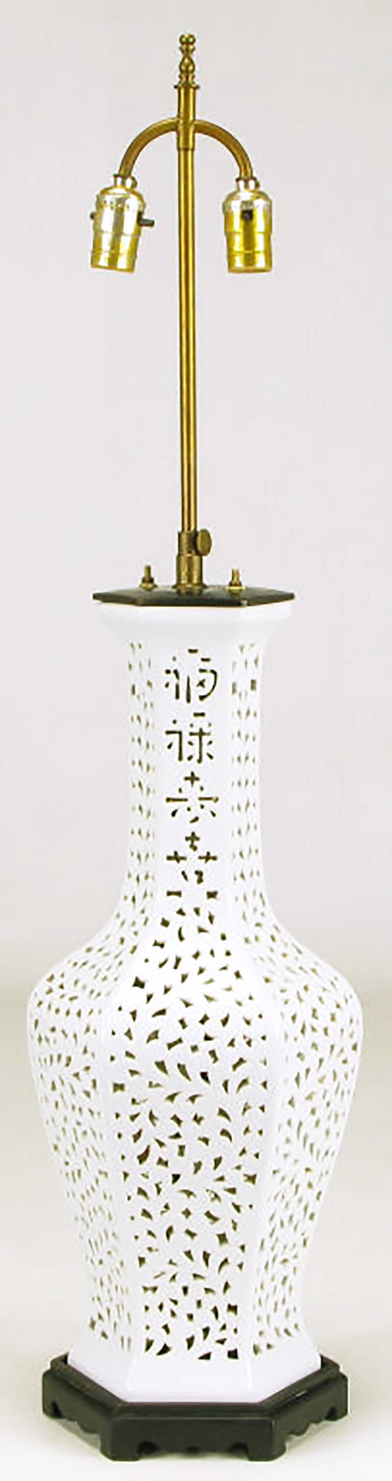 Reticulated Blanc de Chine table lamp in hexagonal vase form, with Asian character design in the neck. Black lacquered wood base and metal cap with brass stem and dual socket illumination. Sold sans shade.