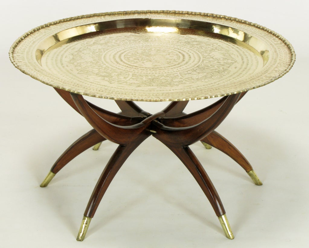 Removable etched brass tray table with Moroccan styling. Mahogany six leg base thats fold down to flat with suction cup ends and brass sabots. Brass top is etched with floral designs and has pie crust edging.