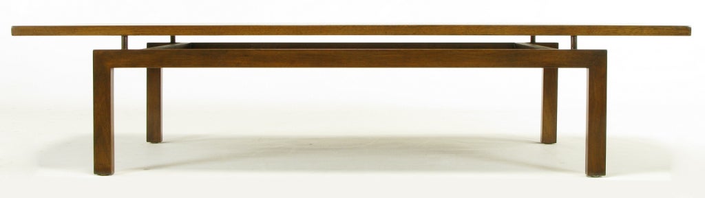 Floating top walnut coffee table after designs by Paul Laszlo for Brown Saltman. Solid three piece top is surmounted atop four wood cylinders. U shaped walnut legs with a pair of inconspicuous recessed stretchers.