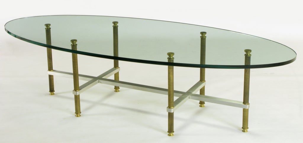 Maison Jansen style eliptical glass top coffee table. Reeded brass legs with nice patinated lacquer and a double cross brushed aluminum square bar stretcher. 5/8