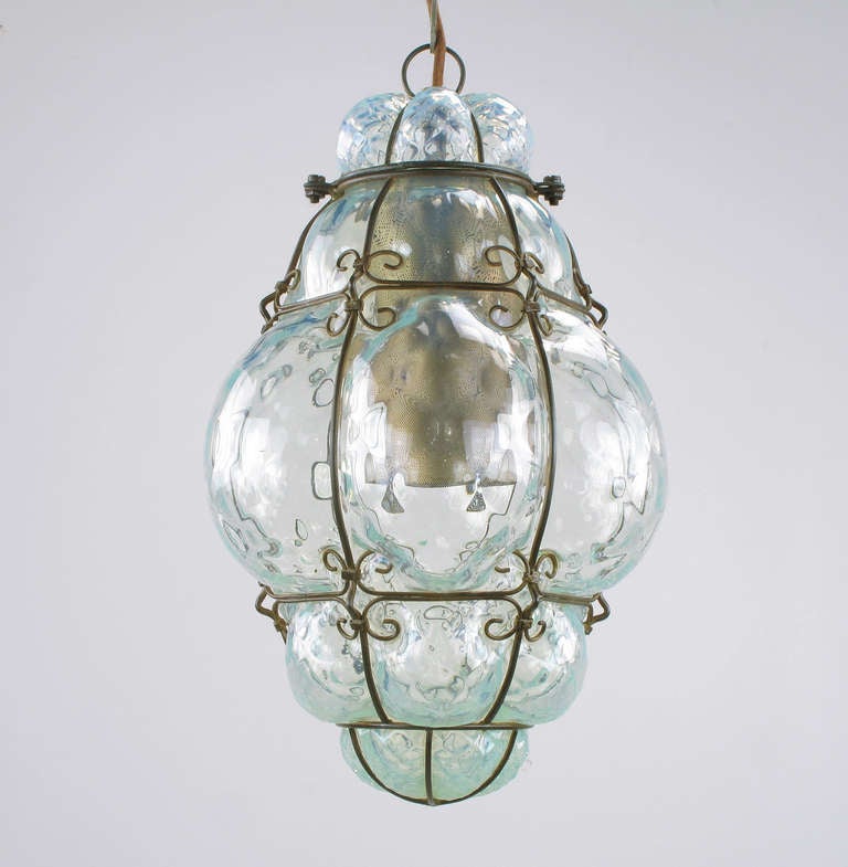 Hand blown Murano blue glass pendant light. Encased in a patinated steel filigreed frame. Single socket illumination with pierced cylinder diffuser.