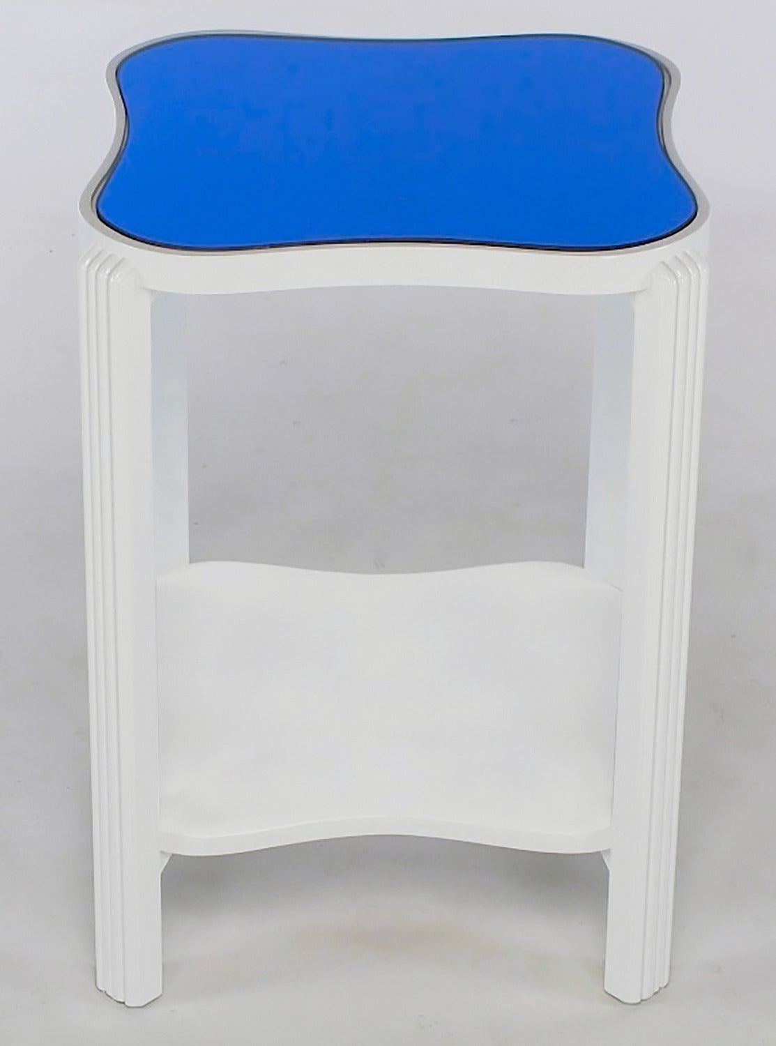 Restored gloss white lacquer over maple Art Deco end table with original blue mirrored top. Squared bow tie shaped two tiered surface; top tier with inset blue mirror and second tier with optional blue mirror or gloss white lacquer. Fluted front