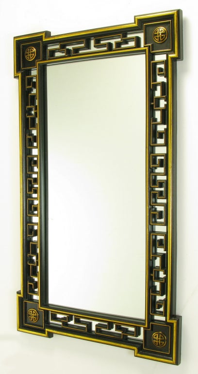 Miroir de style asiatique de 55 pouces de haut, laqué noir et doré à la feuille, avec cadre percé de style chinois Chippendale sur le cadre. Coins exagérés avec relief elliptique et détails dorés.