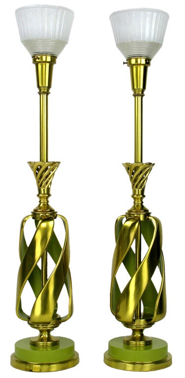 This very heavily constructed pair of solid brass table lamps features a spiraling open brass body. It is evocative of a pineapple, right up to the cast brass crowns signifying the leaves. Brass stem and milk-glass holophane diffusers with lacquered