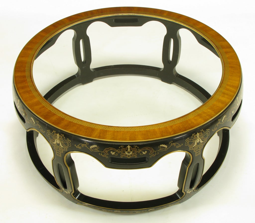 Caved and dark chocolate lacquered wood, open drum form, coffee table. Hand painted gilt and lacquered floral details. Ribbon mahogany rimmed top with gilt Greek key border and inset glass.