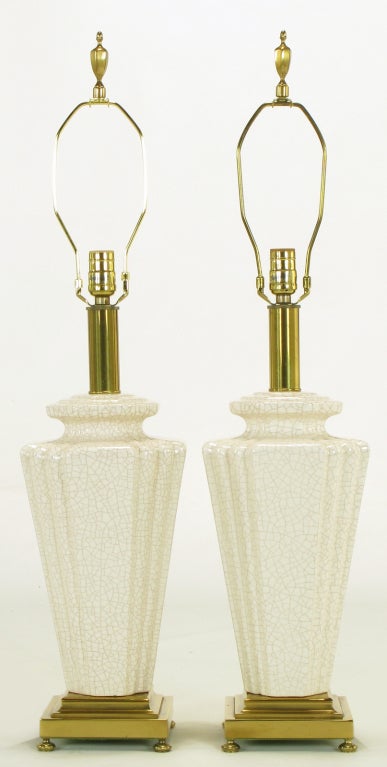 Elegant lamps with ceramic bodies in urn-form, with stepped-back corners, finished in an off-white craquelure glaze. The base is finished in brass, with brass bun feet. Original finials. Sans shades.