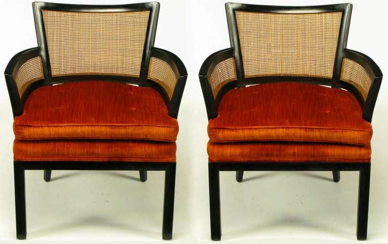 Pair of ebonized mahogany and cane arm chairs by Baker Furniture. Stacked and loose seat cushion is upholstered in a button tufted persimmon velvet. Most likely a Michael Taylor or Winsor White design.

For best price and shipping options, please