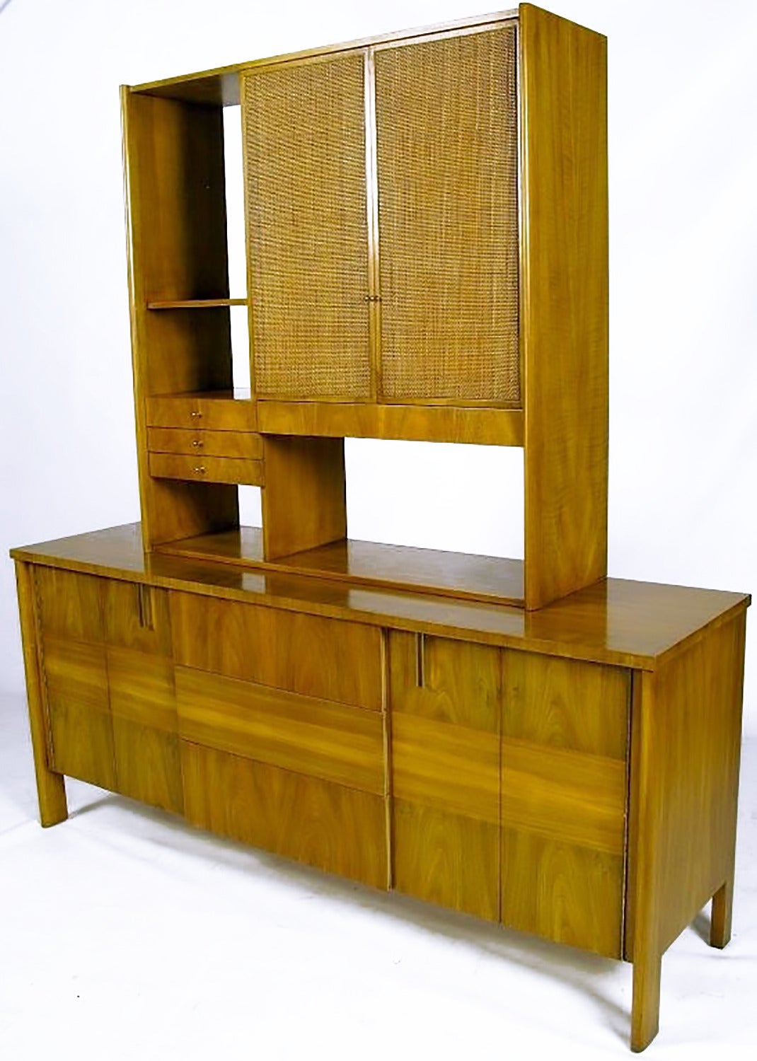 An excellent use of grain pattern and direction create a clean and striking cabinet from John Widdicomb. The cane front doors and open back of the upper piece create depth and add color. Can also be used as credenza. From designer Dale Ford's