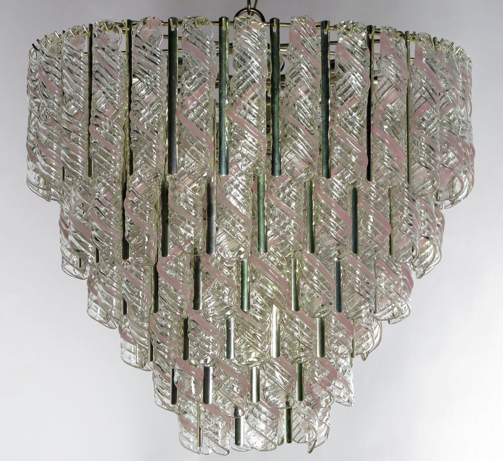 A large and stunning fixture, composed primarily of clear and pink glass canes fused together into nearly foot-long spirals, separated by narrow brass lacunal panels. Lovely when lighted, or even just in daylight.



In addition to this chandelier,