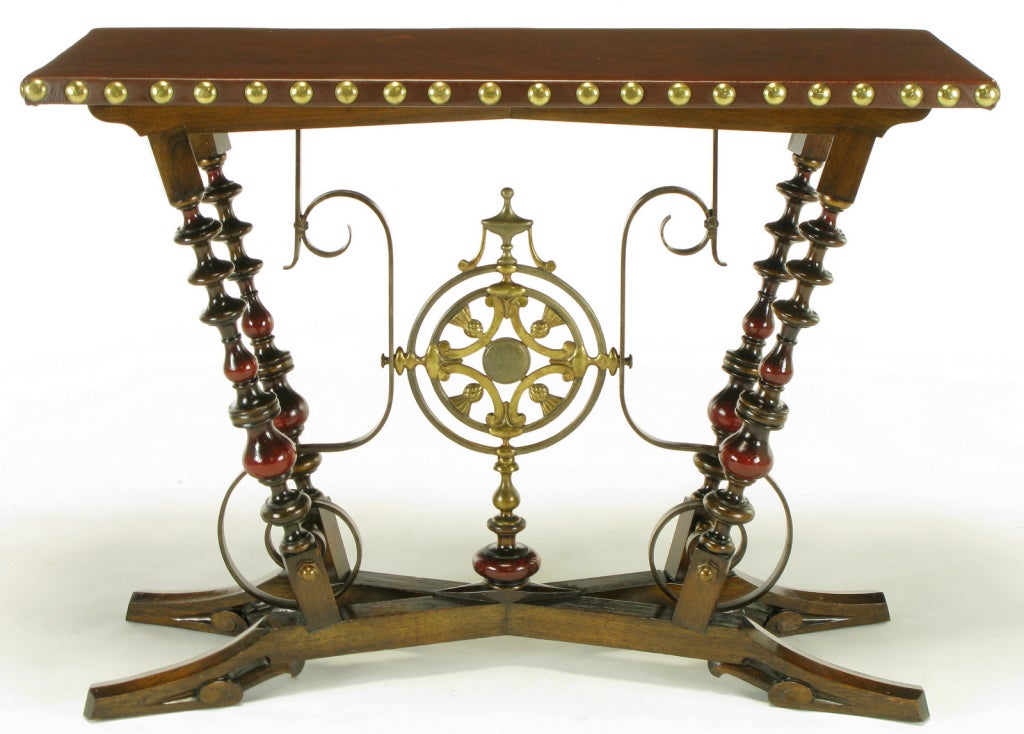Rare Aesthetic Movement inspired console table comprised of carved woods in oak and mahogany with center medallion of gilt iron with thistle ornamentation, and sinuous iron supports . X-form base with four legs and wood covered leather top with