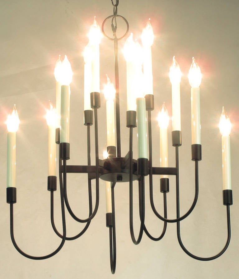 Elegante lampadario a sedici luci in lacca nera di Lightolier. Il design è spesso attribuito a Tommi Parzinger. Il lampadario è composto da otto raggi che si dipartono dal disco centrale e ogni barra contiene due luci su un'asta curva. Viene fornito