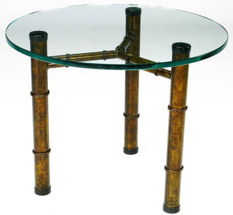 Excellent and heavy side table in an aged and stylized bamboo form with three sturdy legs and a connecting Y-stretcher. The round glass top is 1/2