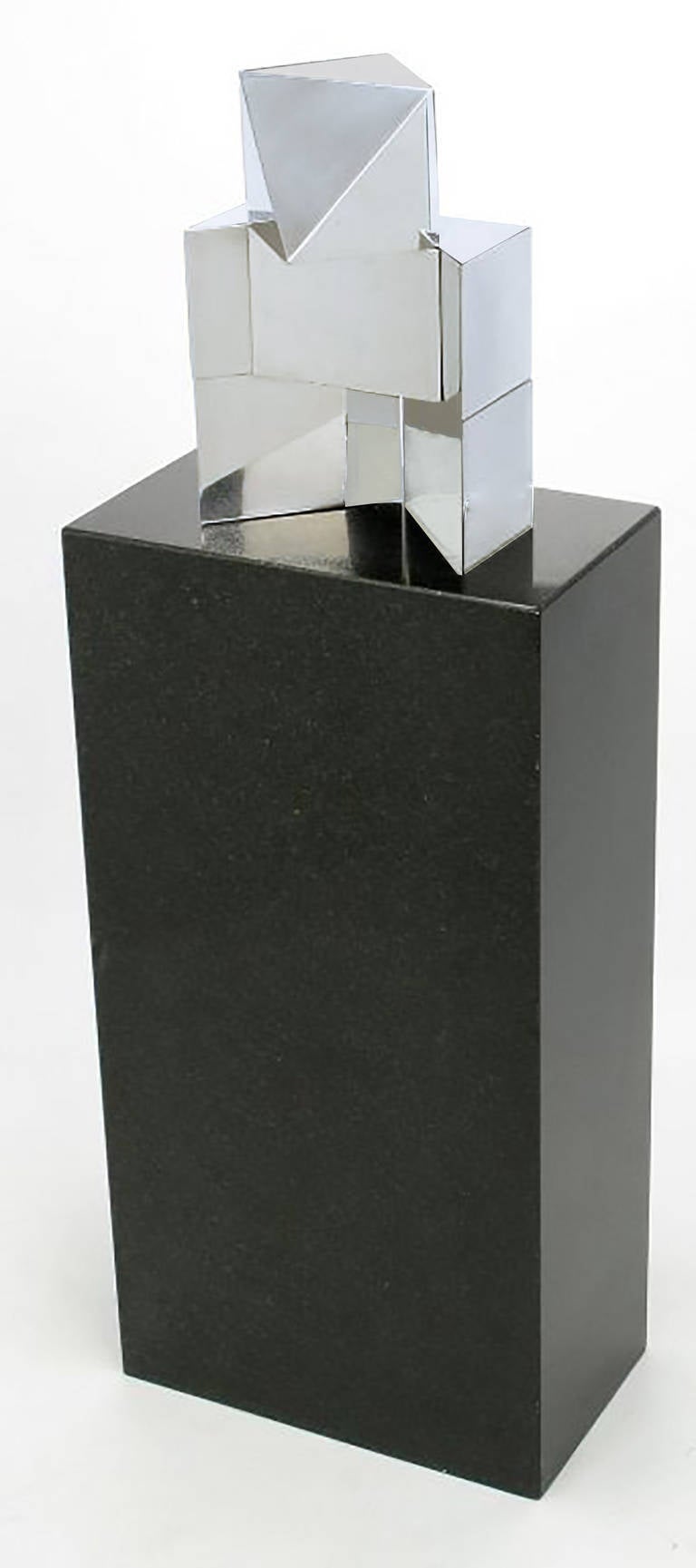 Impresionante escultura geométrica de metal cromado e inciso, sobre un zócalo de granito negro. La escultura está firmada por S. Fernandez Van Den Bussche 1979.