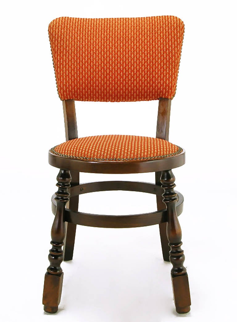 Unexpected set of four uncommon Neo Gothic style dining chairs with baluster style front legs, round bentwood stretchers and circular seats. Upholstered in a textured persimmon and ivory patterned wool with brass nailhead appointments. These would