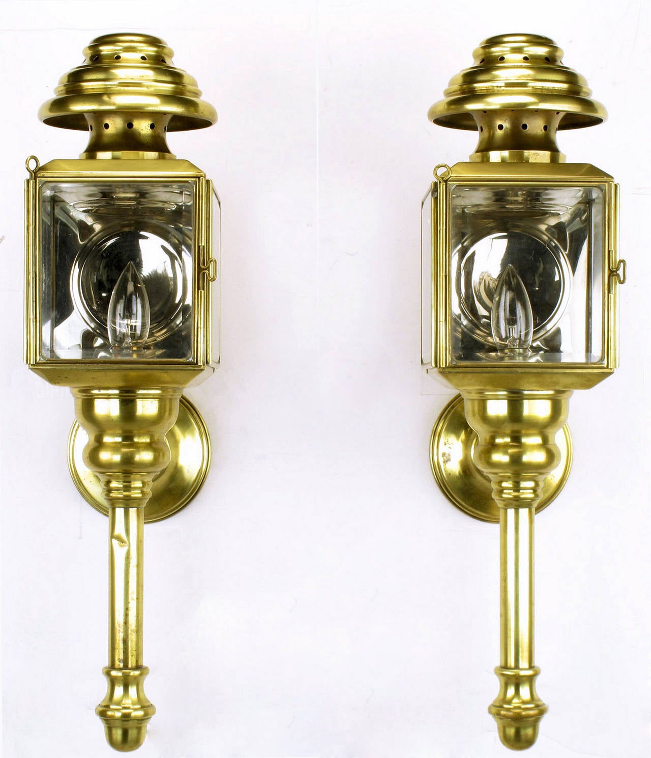 Pair of solid brass coach lights or sconces converted from gas to electric. Original beveled glass panes. Original silvered brass interior top, back and bottom for enhanced reflection. Pierced brass chimney with bee hive cap. Uses standard base